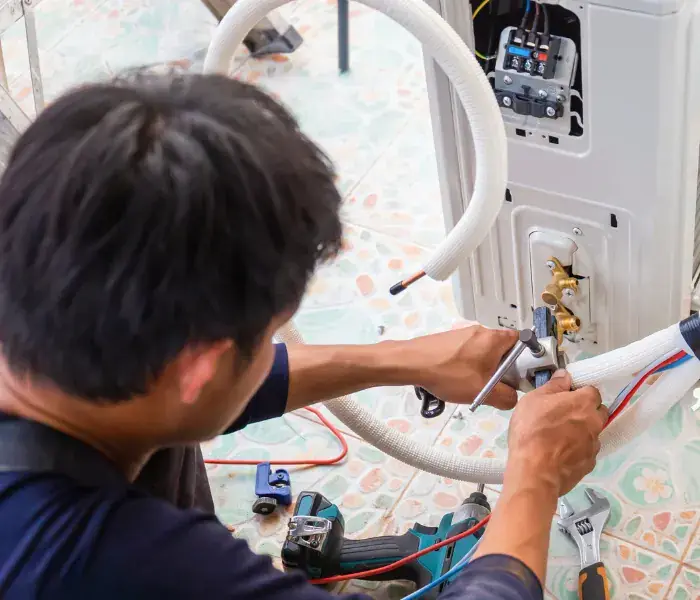 Business air conditioning installation in Bolton Engineer connecting the pipework on a wall-mounted air conditioning unit