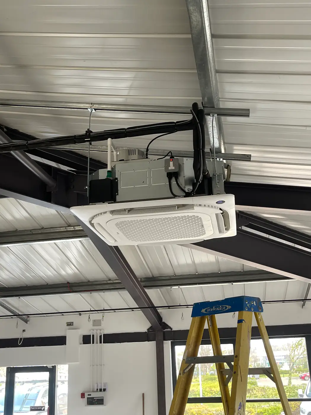 Commercial air conditioning by our Manchester engineers Ceiling cassette unit installed on exposed steelwork in a warehouse